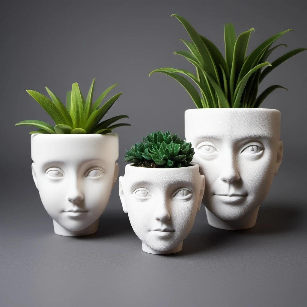 Three white 3d printed face planters with green succulent plants on a gray background.